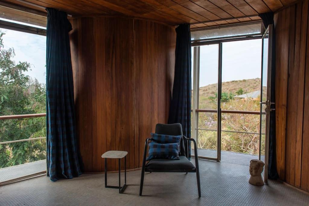a chair and a table in a room with windows at Bâtiment Ovale in Toubab Dialaw