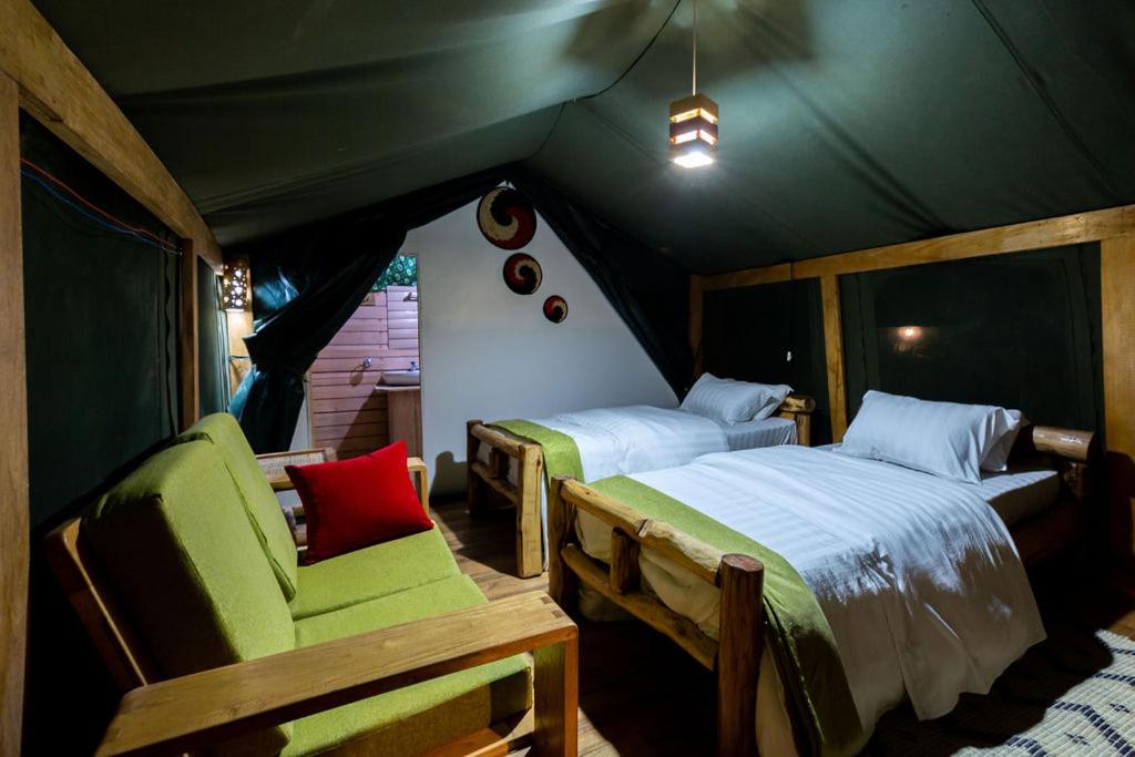 a tent bedroom with two beds and a chair at Ruhondo Island Retreat in Ruhondo