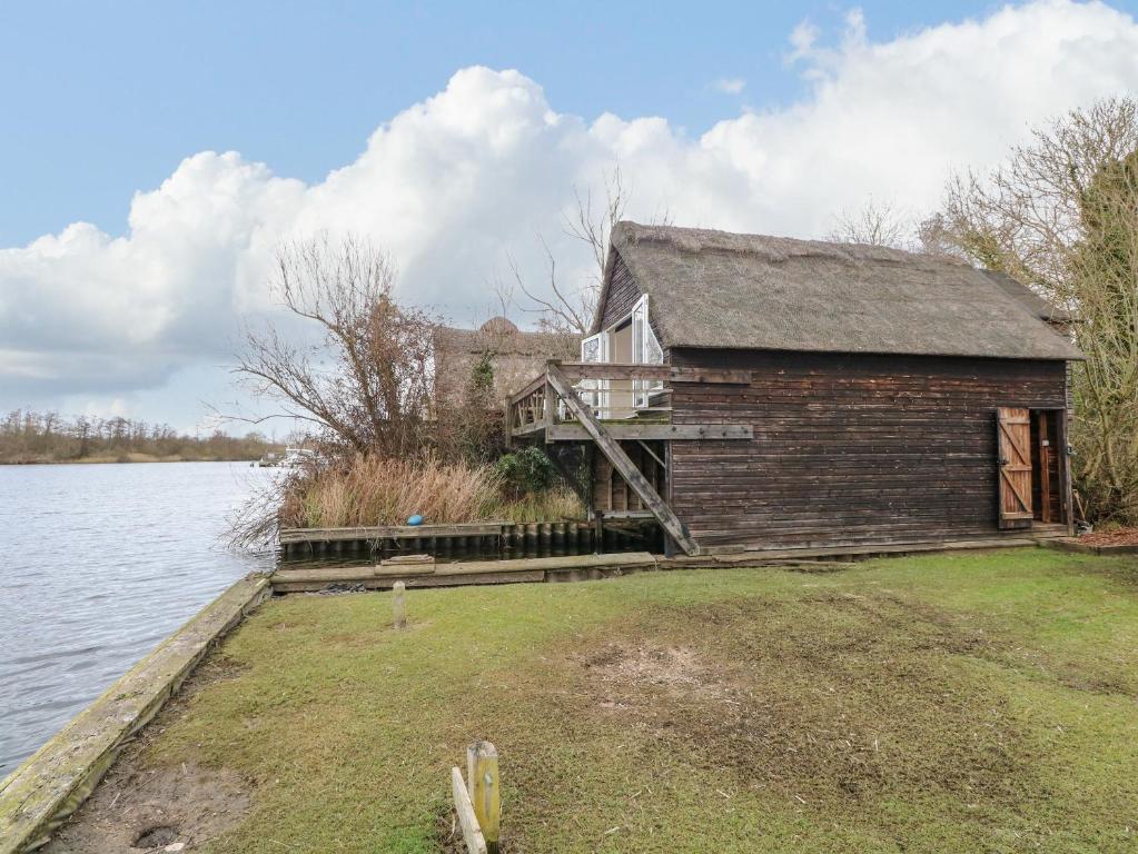 a house on the shore of a body of water at Cygnus Boathouse in South Walsham