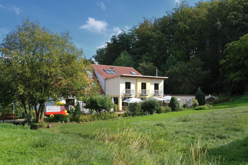 una casa bianca con un tetto rosso su un campo verde di Landgasthof Mücke a Marsberg
