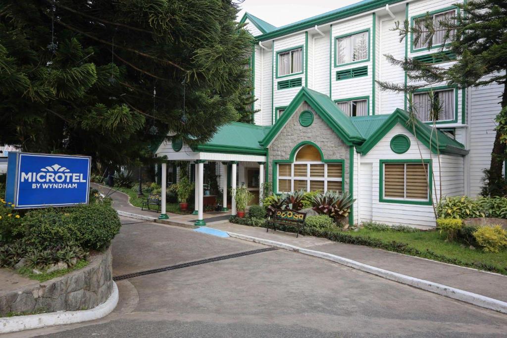uma casa com um sinal em frente em Microtel by Wyndham Baguio em Baguio