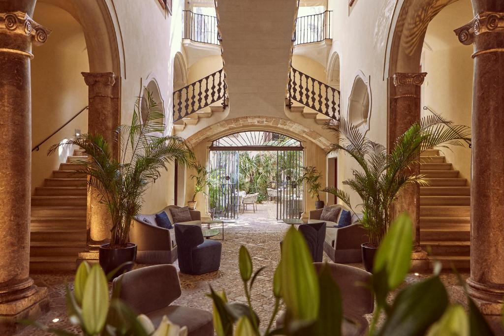 einen Flur mit Treppen, Stühlen und Pflanzen in der Unterkunft Palacio Can Marqués in Palma de Mallorca
