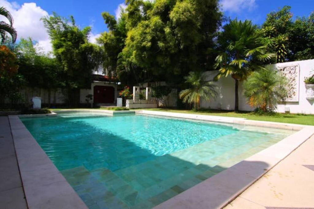 a swimming pool with blue water in a yard at White Moon - Dream 5br Villa in Legian close to the Beach in Kuta