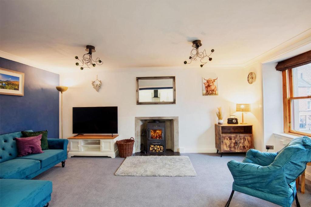a living room with blue furniture and a fireplace at Unique 2 Bedroom Flat Kirrie Scotland in Kirriemuir