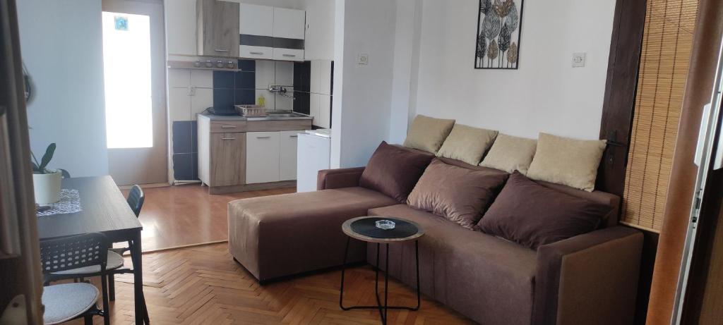 a living room with a brown couch and a kitchen at Apartment Mina in Soko Banja