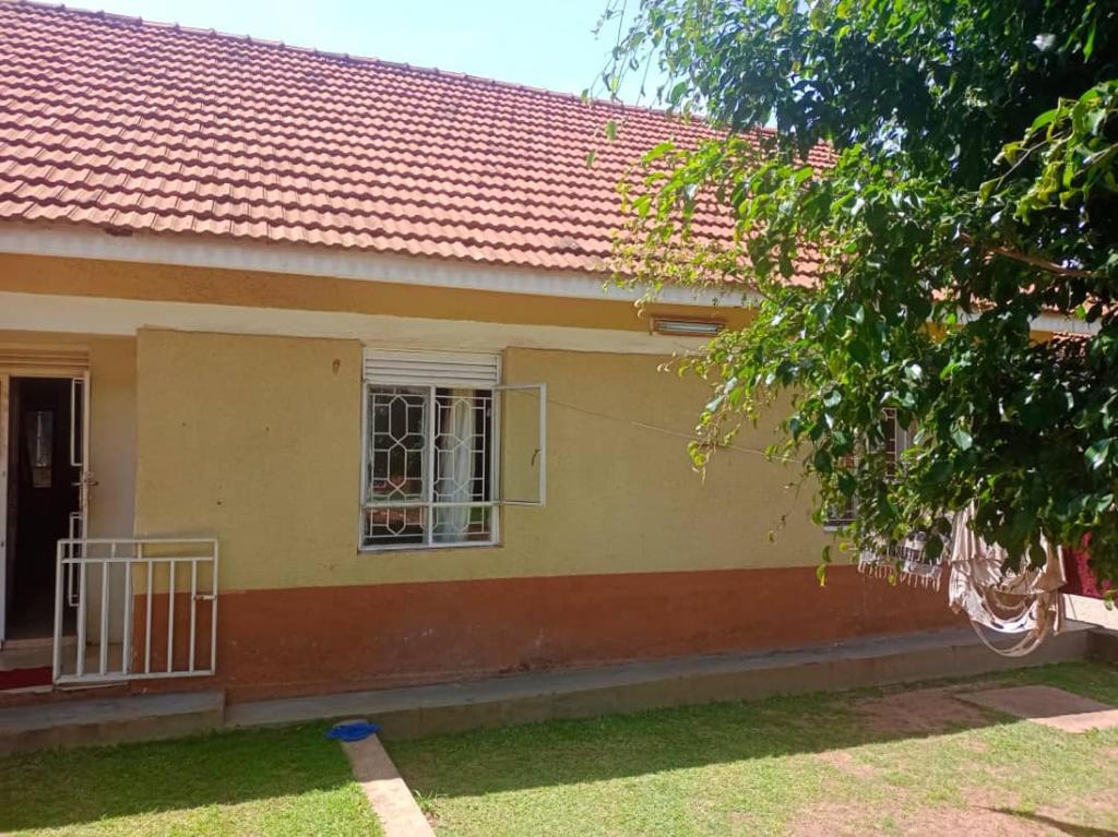 a yellow house with a red roof and a window at Abid's Homestay in Kampala
