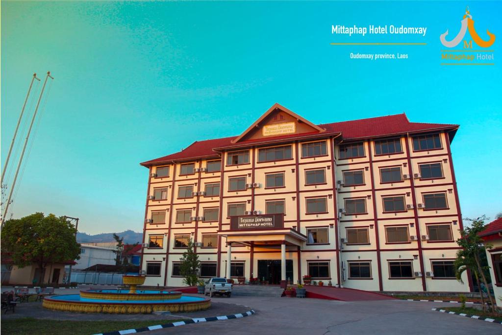 a large tan building with a red roof at Mittaphap Hotel Oudomxai in Muang Xai