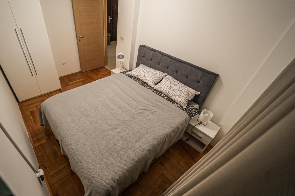 a bedroom with a large bed with a gray headboard at URBAN GREY APARTMAN in Sremska Mitrovica