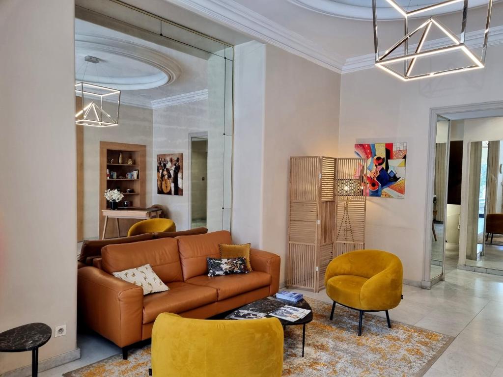 sala de estar con sofá marrón y sillas amarillas en Hotel Carlton Nice, en Niza