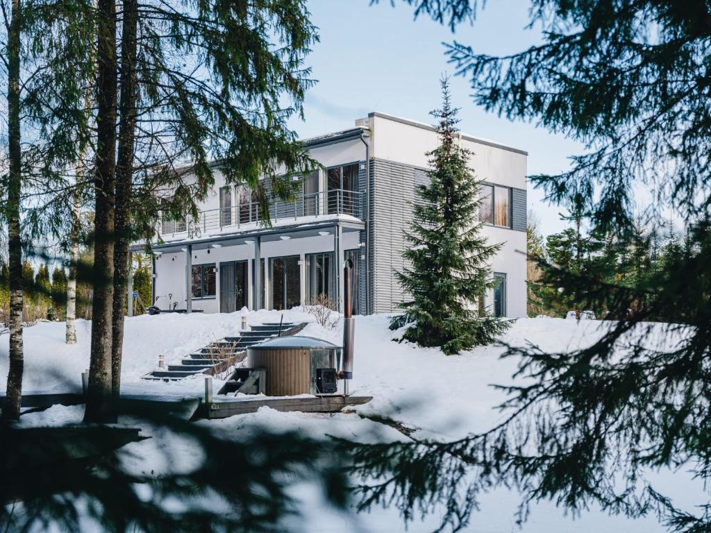 a house in the snow with trees in the foreground at Villa Saskia in Otepää