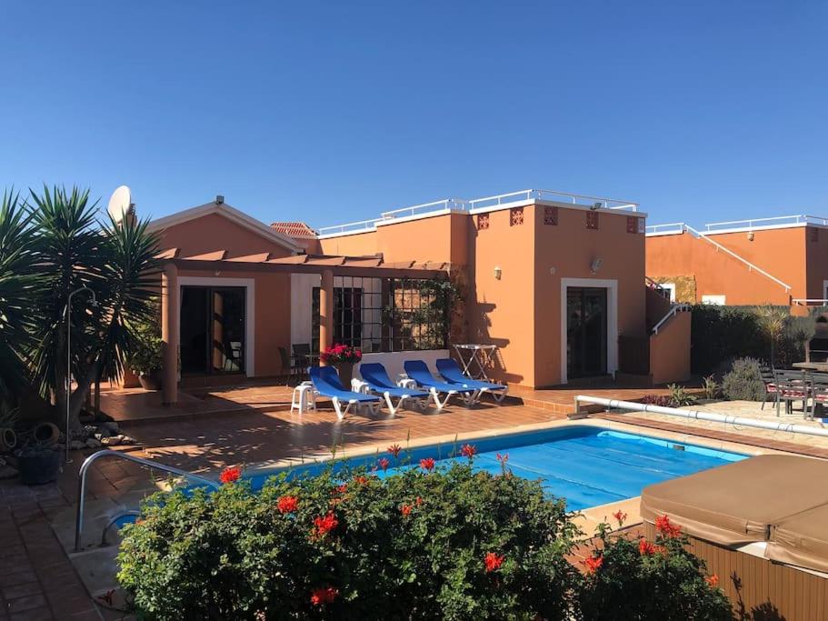 a house with a swimming pool in front of a house at Casa Piedra, Luxury Family Front Line Golf, Hot Tub,Pool Table, 8 pers, Caleta de Fuste in Caleta De Fuste