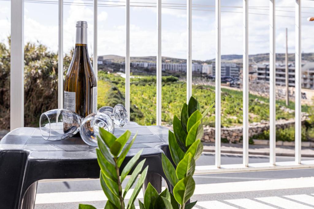 a bottle of wine sitting on a table with a plant at Seaside Flat with Scenic Country Views in Mellieħa
