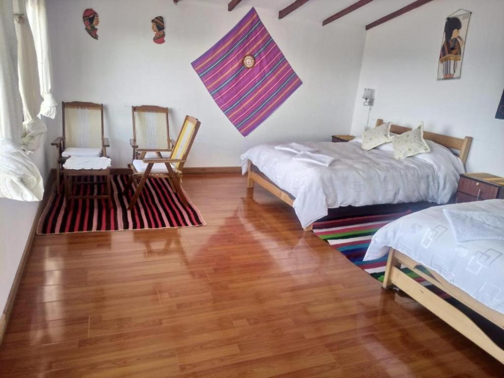 a bedroom with two beds and two chairs at Hostal Inca Uma in Comunidad Yumani