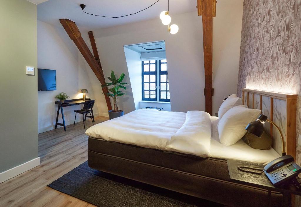 a bedroom with a bed and a desk in a room at Hotel Botanique Breda in Breda