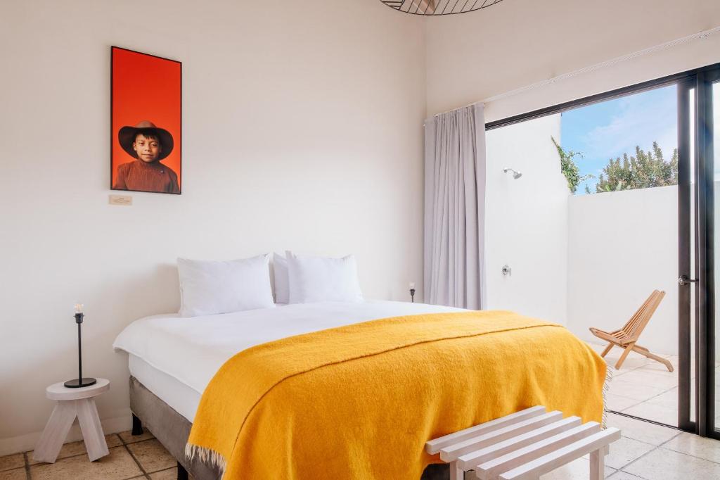 a bedroom with a large bed with a yellow blanket at Good Hotel Antigua in Antigua Guatemala
