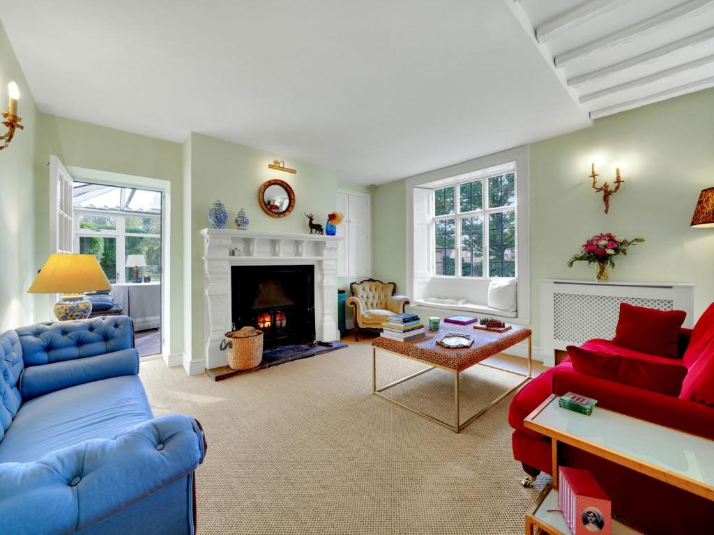 a living room with blue and red furniture and a fireplace at Pass the Keys Sunset House18th cent cottage stunning garden in Chipping Norton