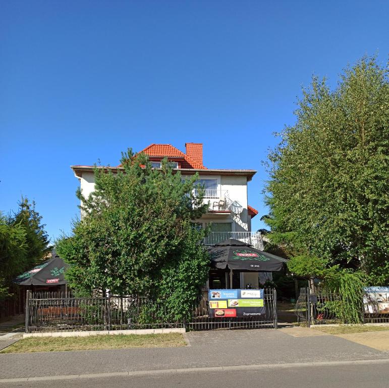 budynek z płotem i drzewami przed nim w obiekcie Bursztyn w Rewalu