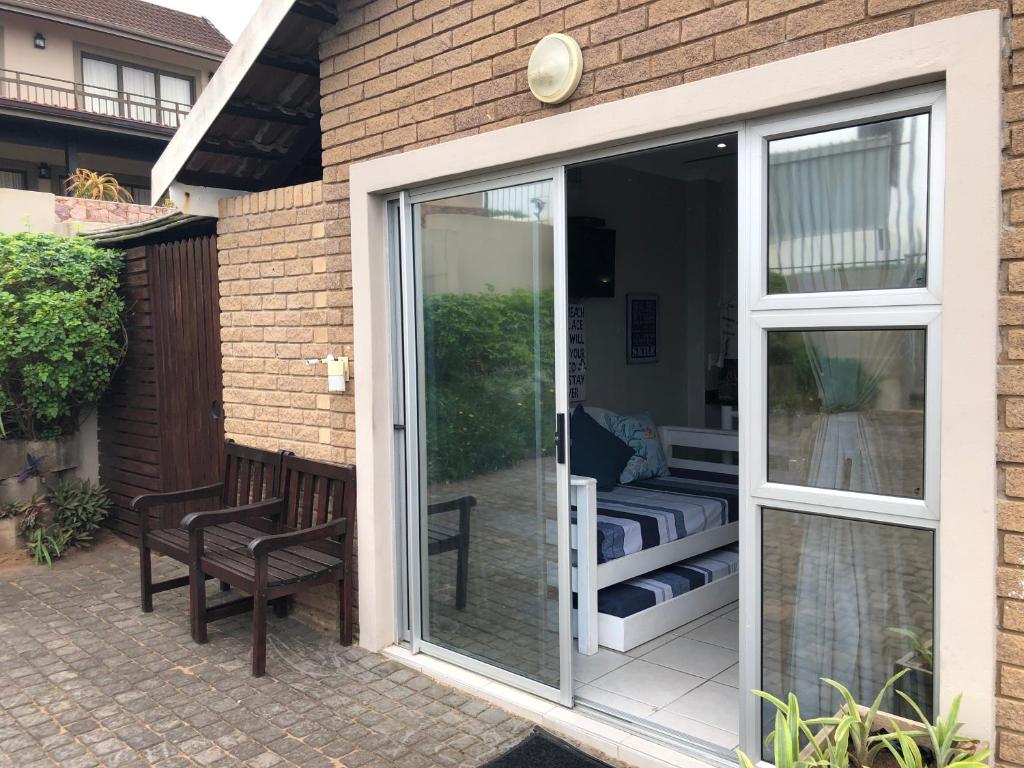 une porte coulissante en verre sur une terrasse avec un banc dans l'établissement 8 Ocean Drive Self Catering Unit, à Ballito