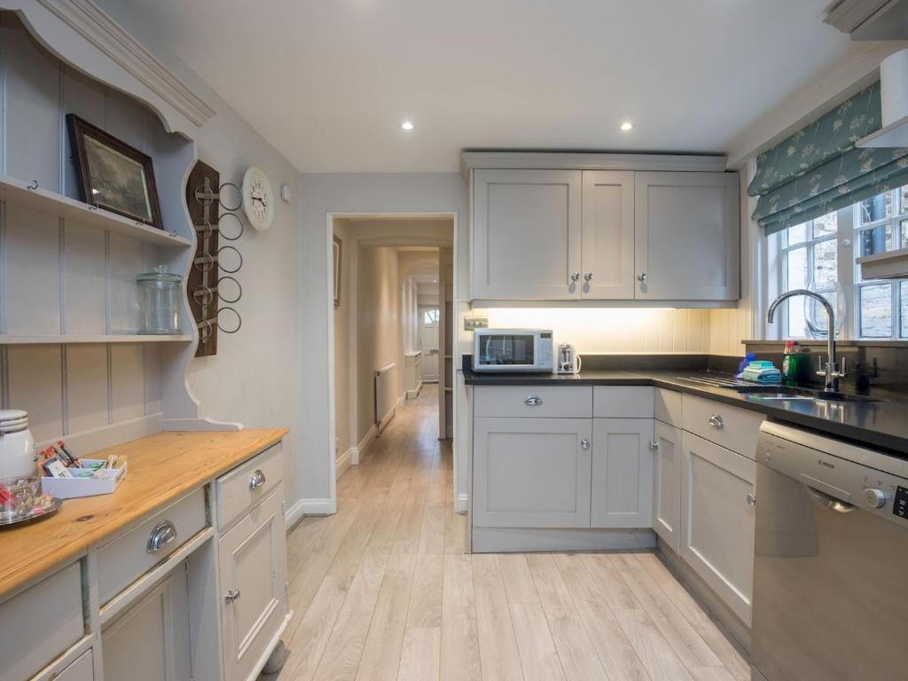 a kitchen with white cabinets and a wooden floor at Pass the Keys Cosy 6 Sleeper House Central Windsor in Windsor