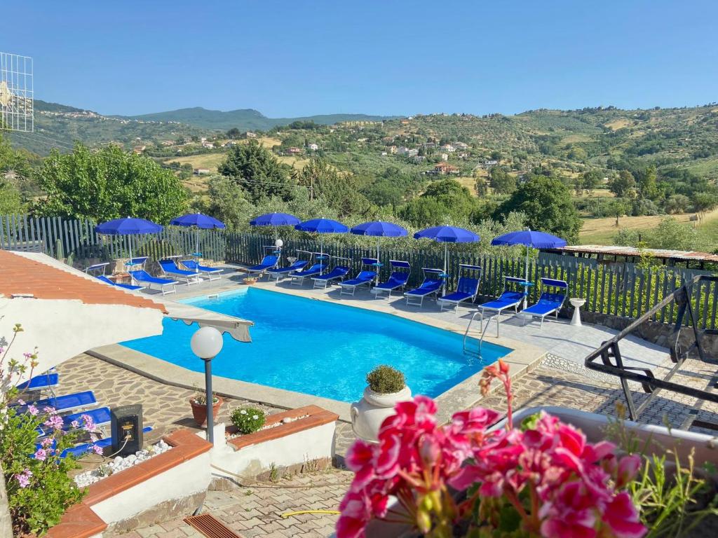 una piscina con sillas y sombrillas azules en Serra Marina Rooms and Apartments, en Santa Maria di Castellabate