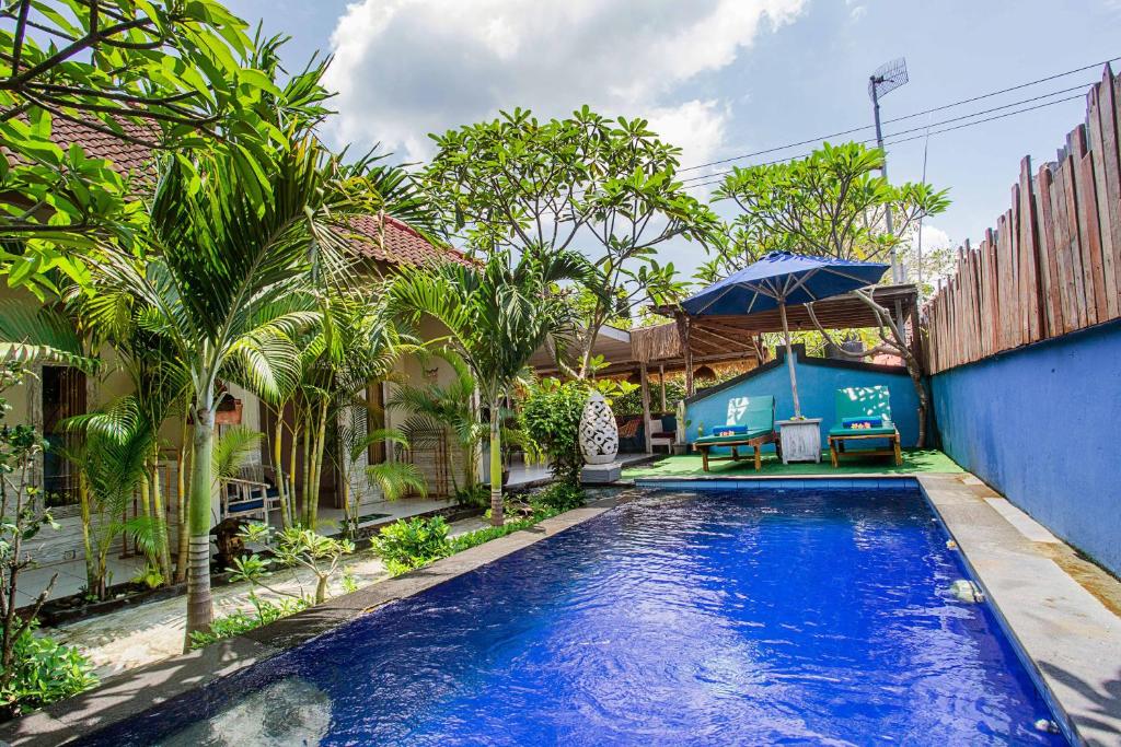 a swimming pool in a yard with palm trees at Naturale Guest House in Nusa Lembongan