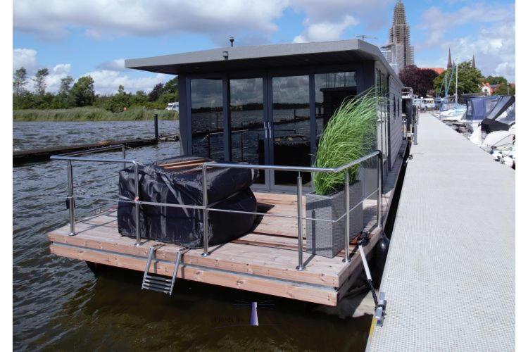ein kleines Boot, das mit einem Dock im Wasser verbunden ist. in der Unterkunft Hausboot Fjord Dory mit Biosauna in Schleswig in Schleswig