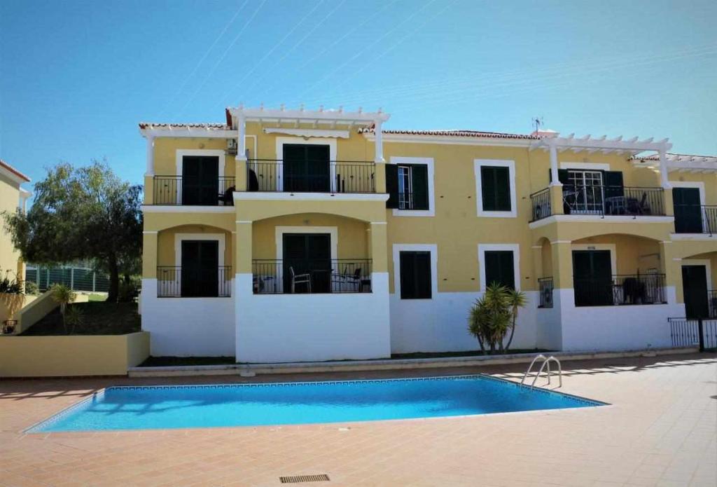 a large yellow house with a swimming pool in front of it at AlgarveSand Porches in Porches