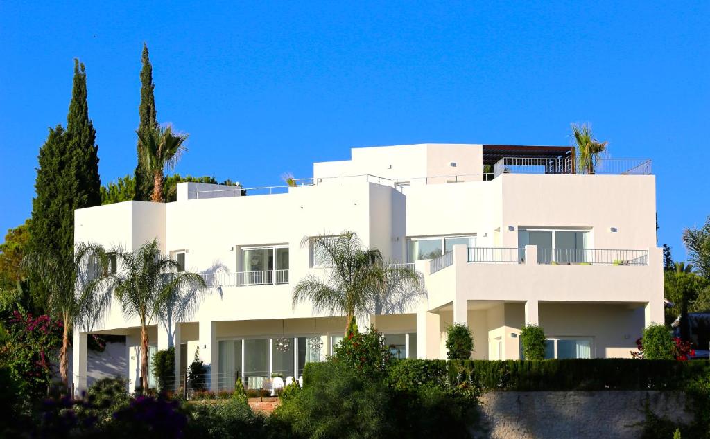a white house with palm trees in front of it at Exquisite Villa Near Beach - Heated Pool in Marbella