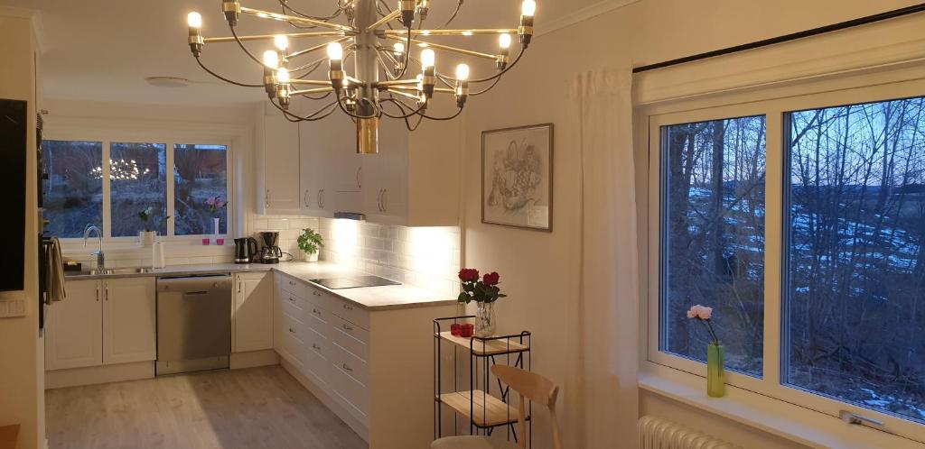 una cocina con armarios blancos y una lámpara de araña en Semesterhus Kymbo Jungfrugården 2 en Falköping