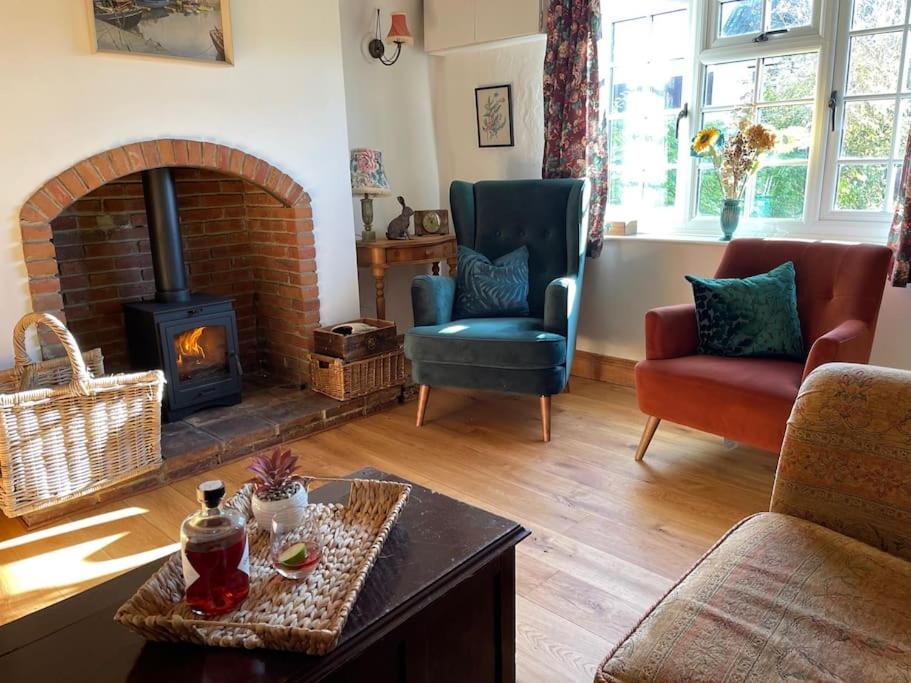 a living room with a fireplace and a couch and chairs at Elm Cottage in Northallerton