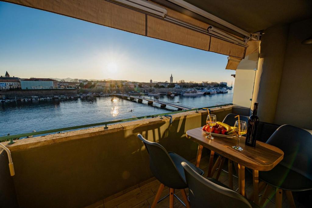 balkon ze stołem i krzesłami oraz widokiem na rzekę w obiekcie Apartment Sundowner w mieście Zadar