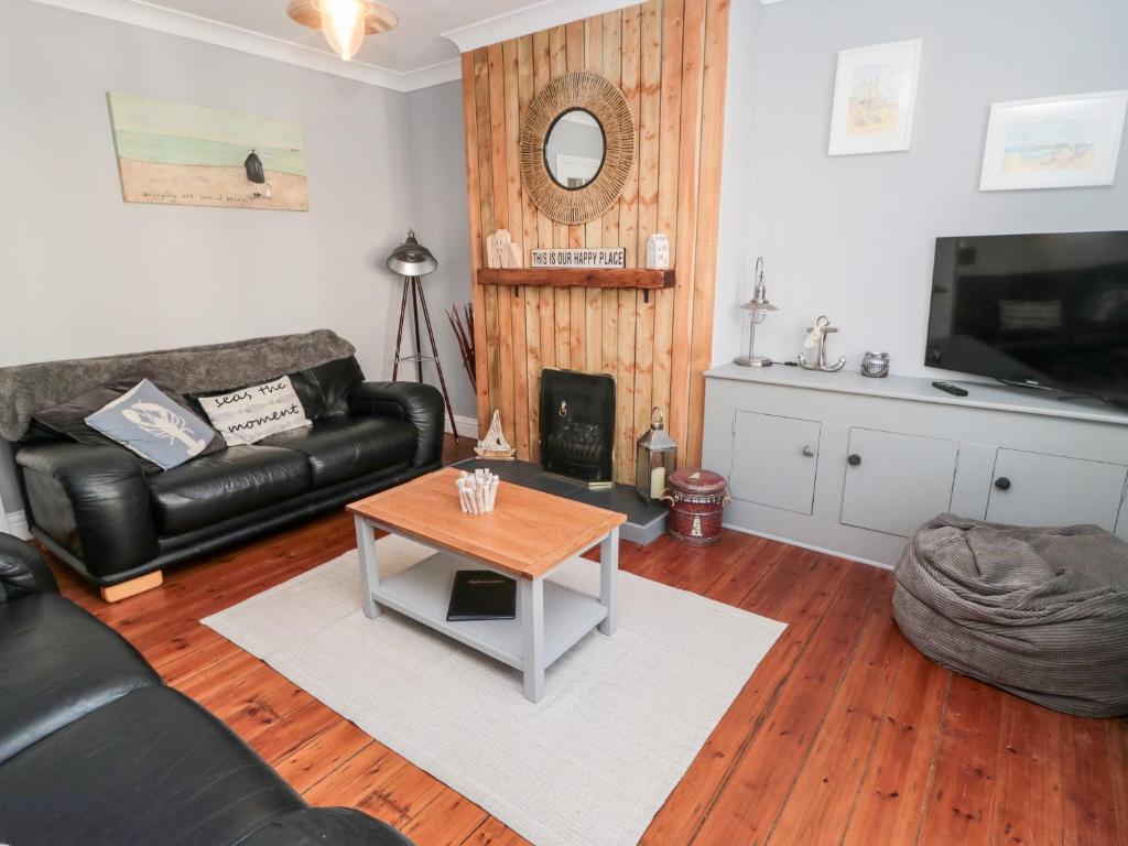 sala de estar con sofá de cuero negro y mesa en 4 Percy Street en Morpeth