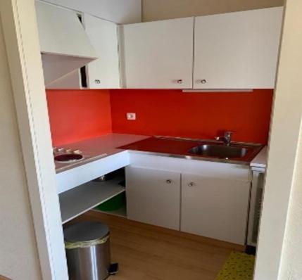 een kleine keuken met witte kasten en een wastafel bij Studio Laguna Beach Knokke-Heist in Knokke-Heist