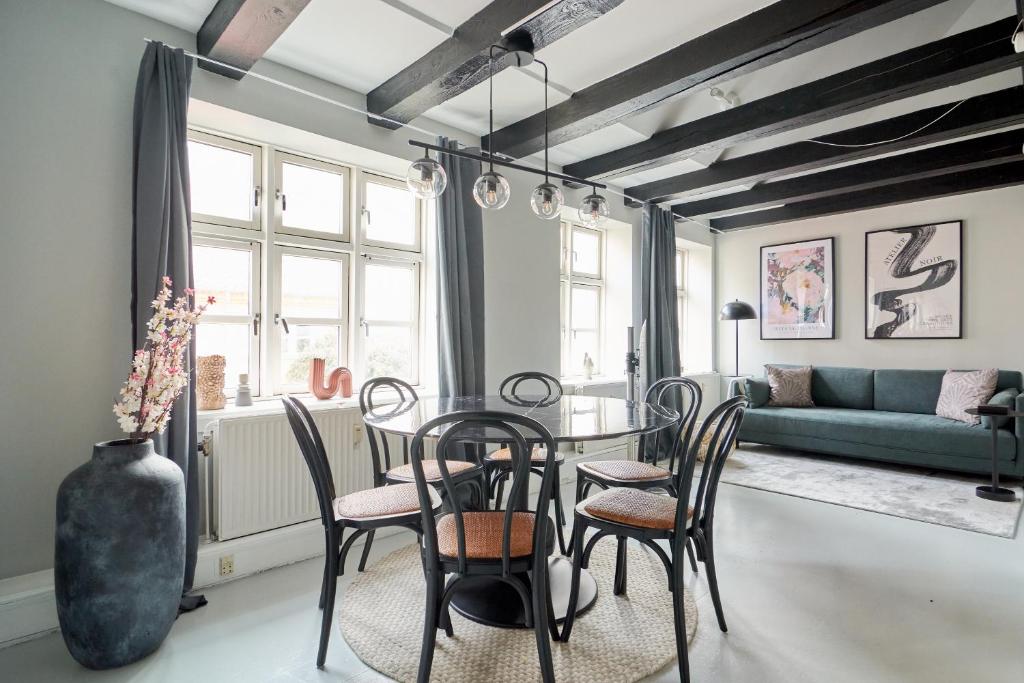 uma sala de jantar com uma mesa e cadeiras e um sofá em Unique 2 Bedroom Duplex w Exposed Beams in CPH City em Copenhague