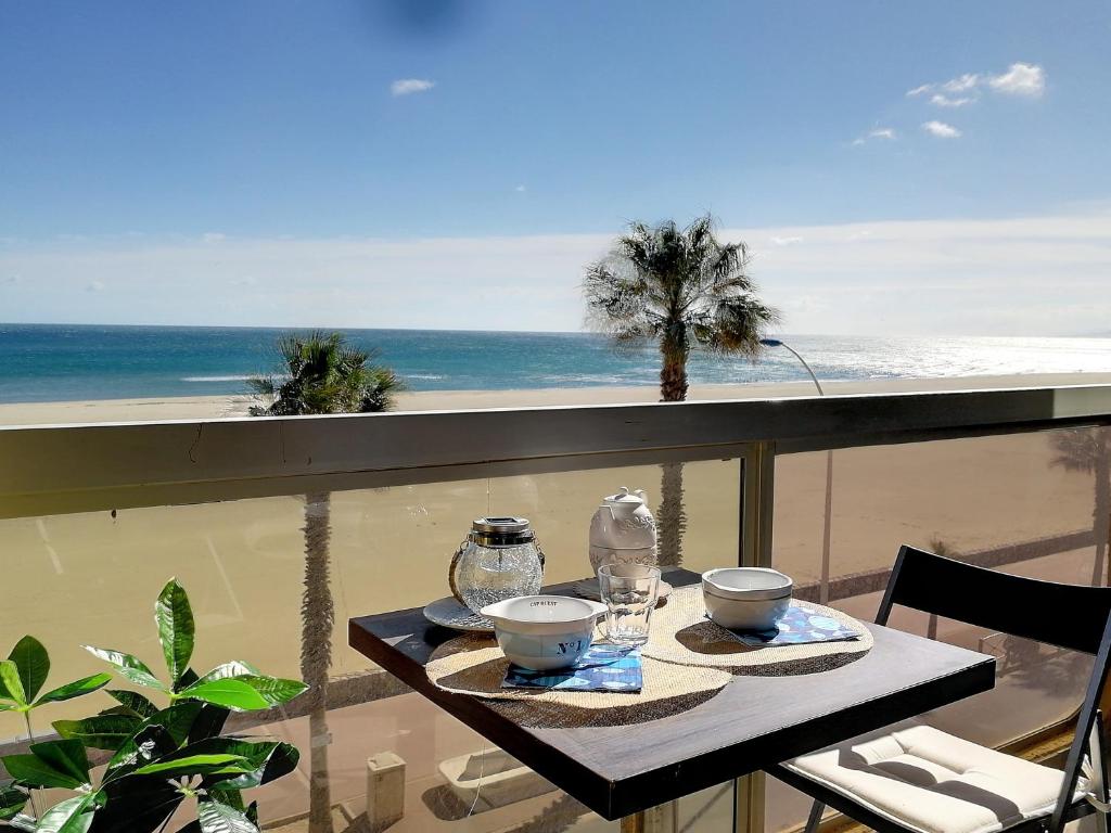 - une table avec des bols et des verres sur un balcon donnant sur la plage dans l'établissement Rêve de plage - Confortable appt pour 2, à Canet