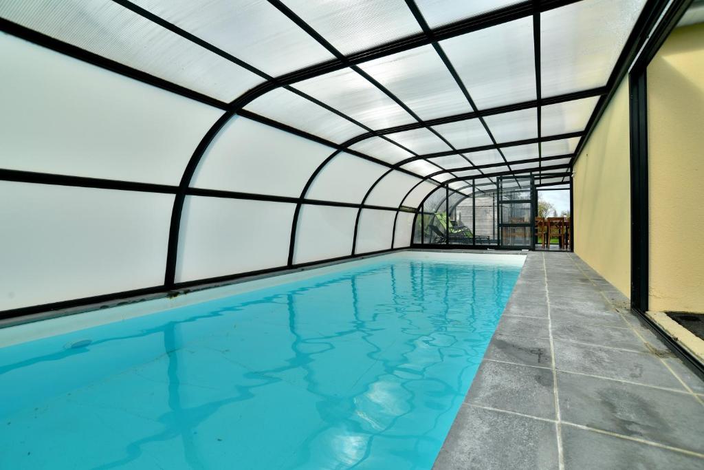 an indoor swimming pool with a glass ceiling at Maison Victoria - avec piscine in Plédèliac