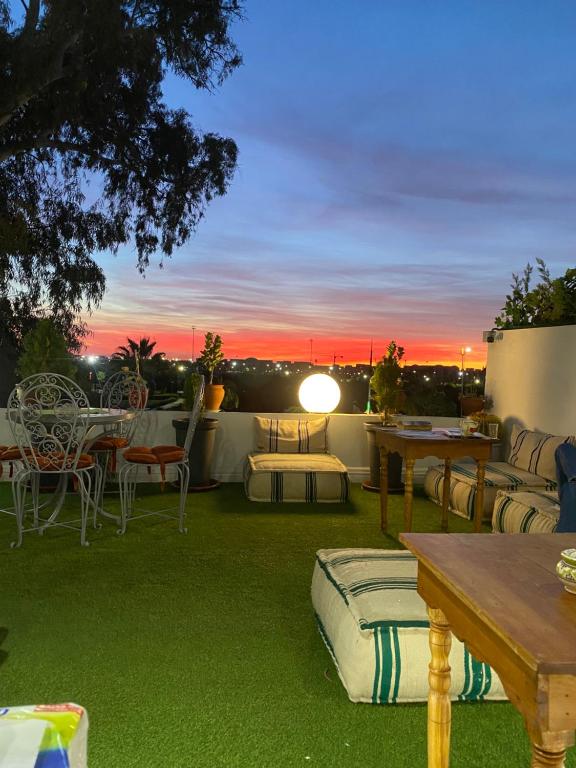 eine Terrasse mit einem Tisch und Stühlen sowie einem Sonnenuntergang in der Unterkunft Winarouze house in Marrakesch