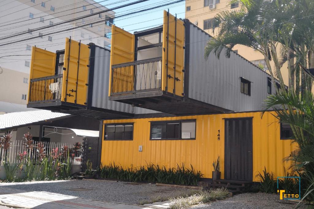 un edificio amarillo con balcones encima en Mini Aps em Container na Meia Praia - Tetto 148 en Itapema