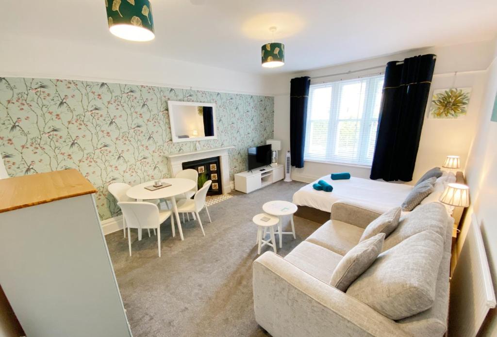 a living room with a couch and a bed and a table at The Chine- A Spacious Studio Close to the Beach in Bournemouth