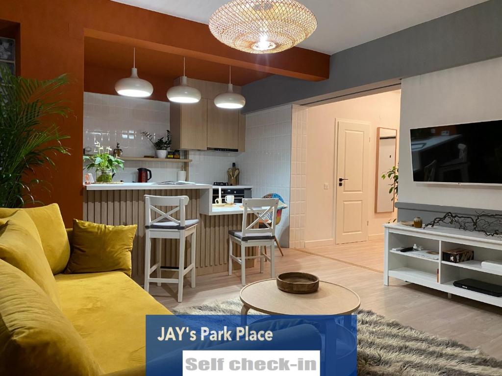 sala de estar con sofá amarillo y cocina en JAY's Park Place en Cluj-Napoca