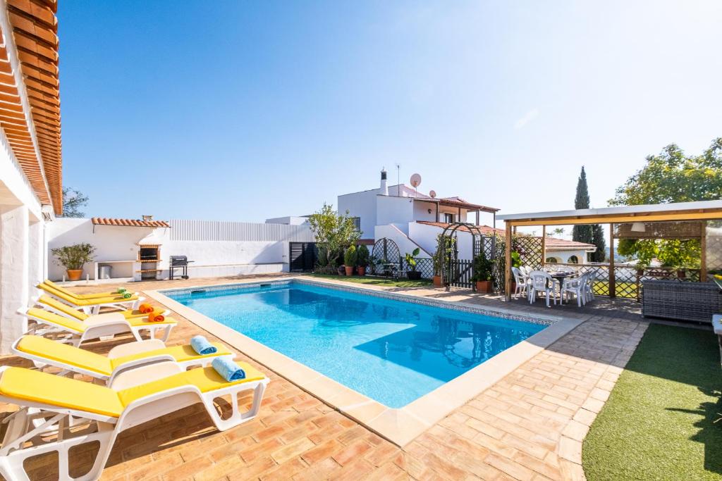 - une piscine avec des chaises et une maison dans l'établissement Villa Estrelícia - Pool - Free wi-fi - New in Booking, à Loulé