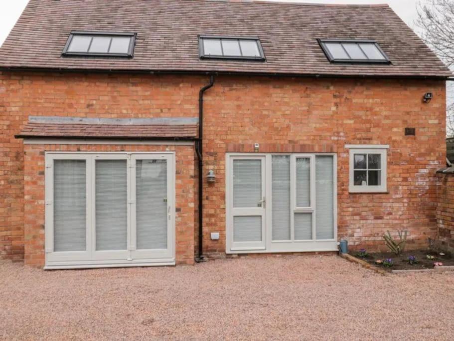 a brick house with two garage doors and windows at The Upside Down House at The Mercers in Worcester