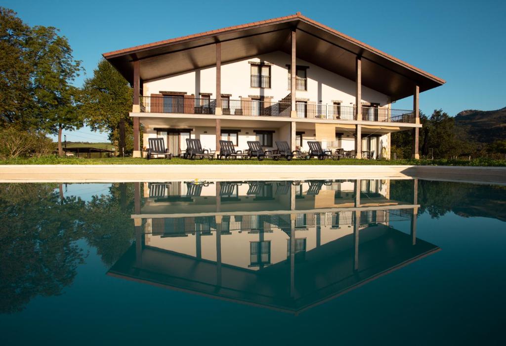 ein großes Haus mit einer Reflexion im Wasser in der Unterkunft Agroturismo BASITEGI in Urnieta