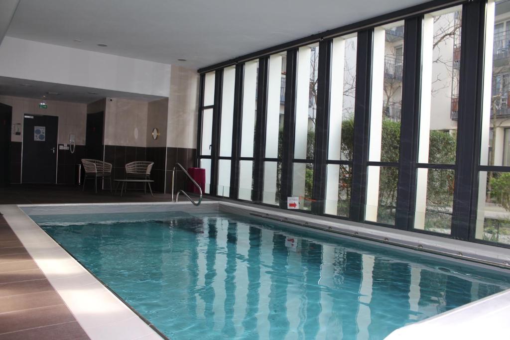 a large swimming pool in a building with windows at Domitys Le Pont des Lumières in Lyon