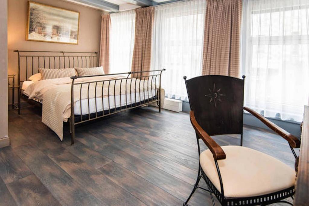 アムステルダムにあるCentral Guest Roomsのベッドルーム1室(ベッド1台、椅子、窓付)