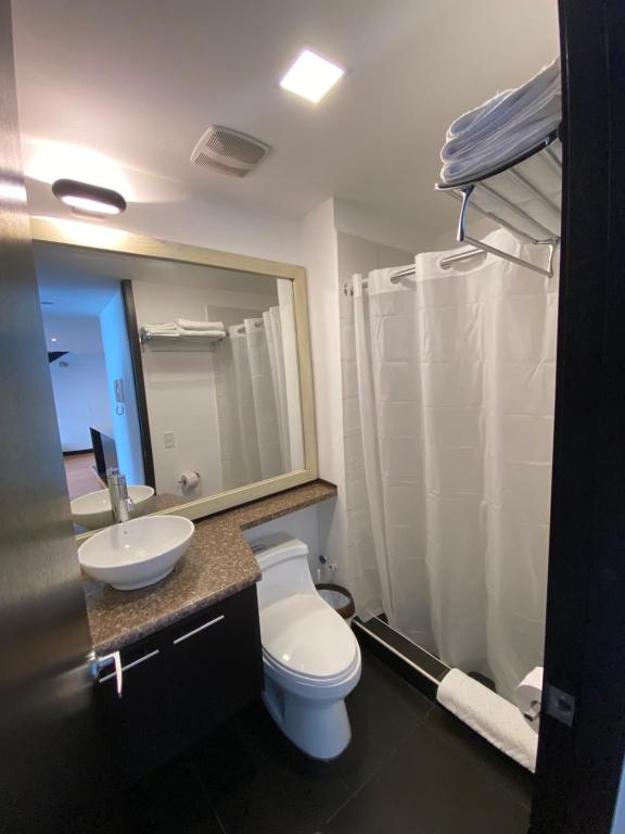 a bathroom with a toilet and a sink and a mirror at Aqua Loft in Quito