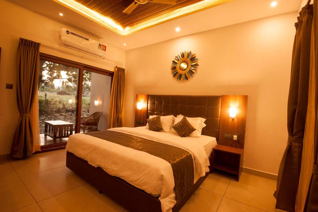 a bedroom with a large bed and a large window at MC Resort Wildlife Resort Bandipur in Bandipūr