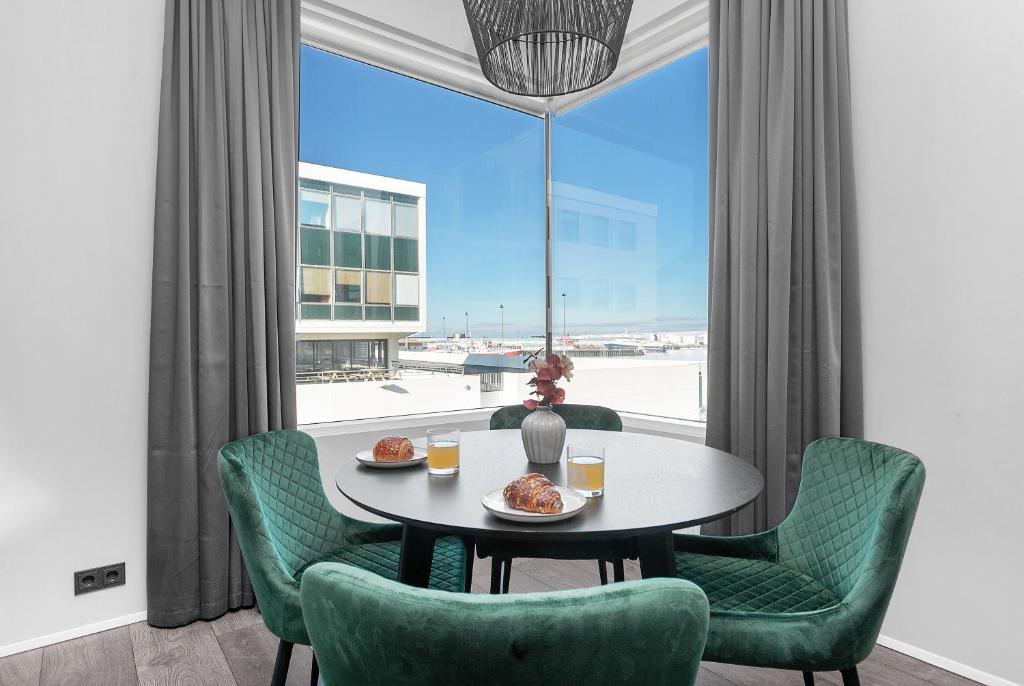 d'une salle à manger avec une table, des chaises et une fenêtre. dans l'établissement Modern Downtown Apartment - Harbour View, à Reykjavik