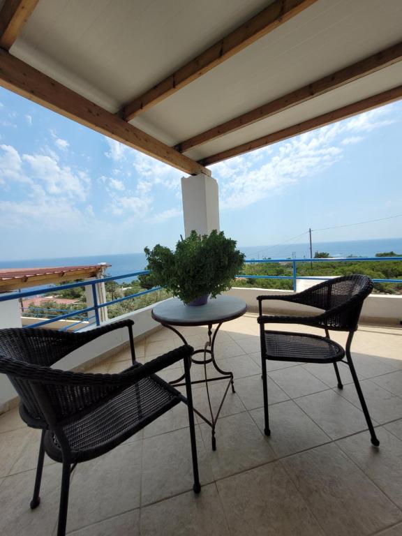 a patio with two chairs and a table with a plant on it at LEFKADA TWINS 4 in Agios Kirykos