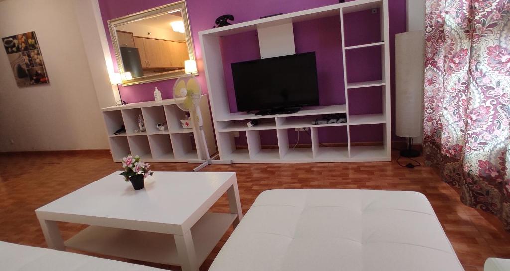 d'un salon avec des murs violets et une télévision. dans l'établissement Apartamento "CASA LOS SABANDEÑOS", à Vecindario